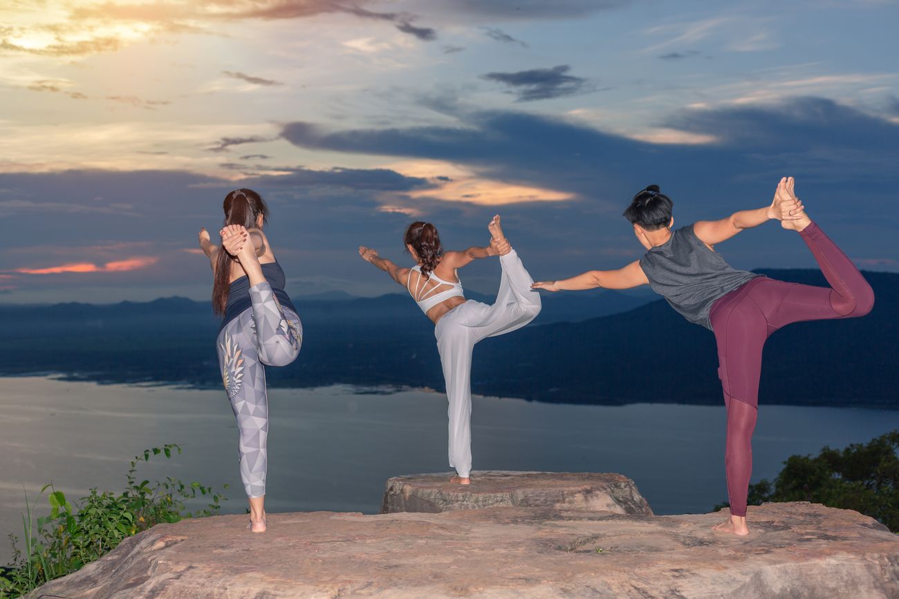 Against the backdrop of the sun setting over the Himalayan ranges, three women perform the Natarajasana, named after the Lord of Dance - Shiva