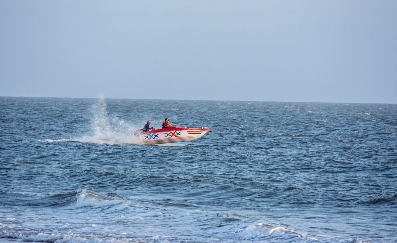 Tourists enjoy a ride at the ocean on a speedboat at the Mandvi Beach of Gujarat as the ocean wind blows fast 