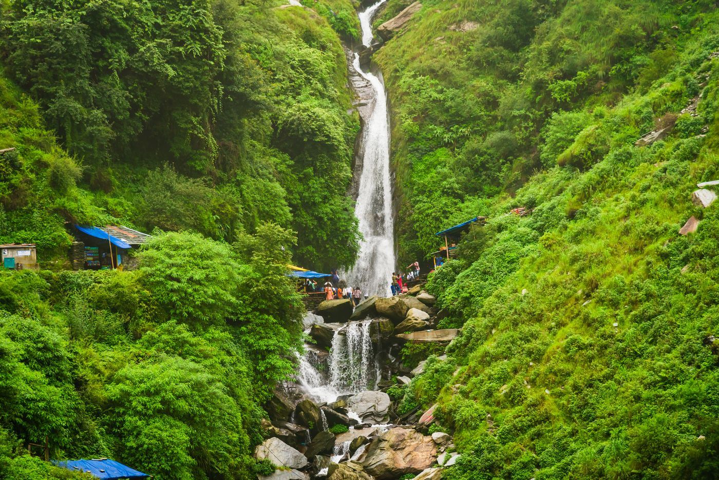 Tourists enjoying the Bhagsu Nag waterfall and surrounding greenery 