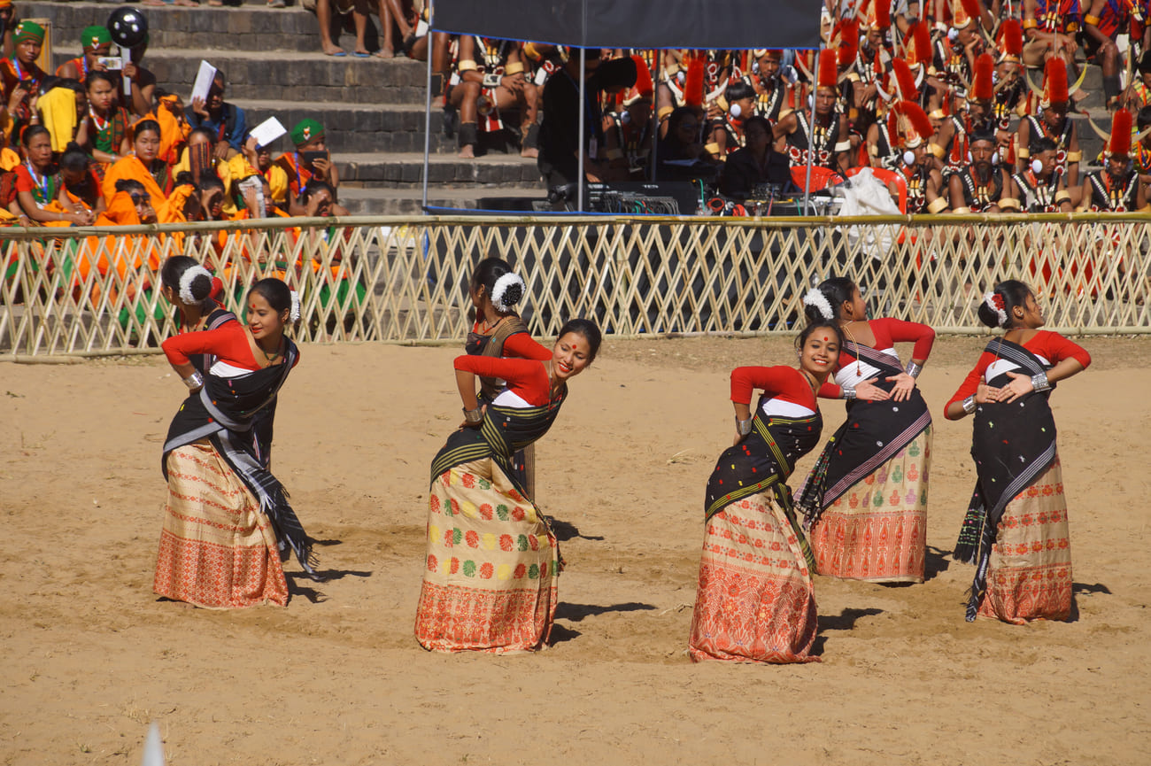 Tribeswomen strike graceful poses during their traditional dance performance in front of an appreciative audience