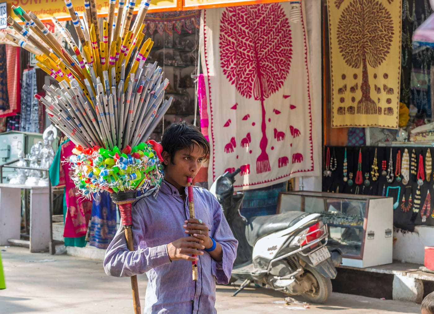 A street vendor advertises his merchandise and lures customers by playing his flute