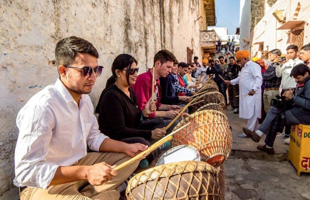 Visitors from around the world eagerly take part in nagada street workshops during the Pushkar Festival. 