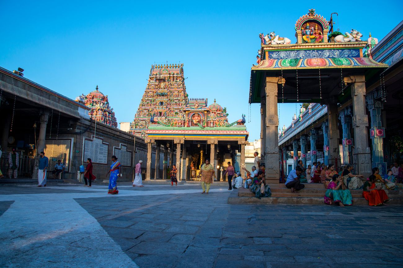 Visitors relax on the steps near the ancient multi-shrined Kapaleeshwatar Temple in Tamil Nadu