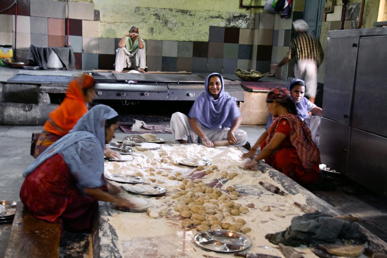 Women preparing food in the kitchen of a Sikh temple in Delhi, India. Sikh temples serve thousands of free meals to the poor every day