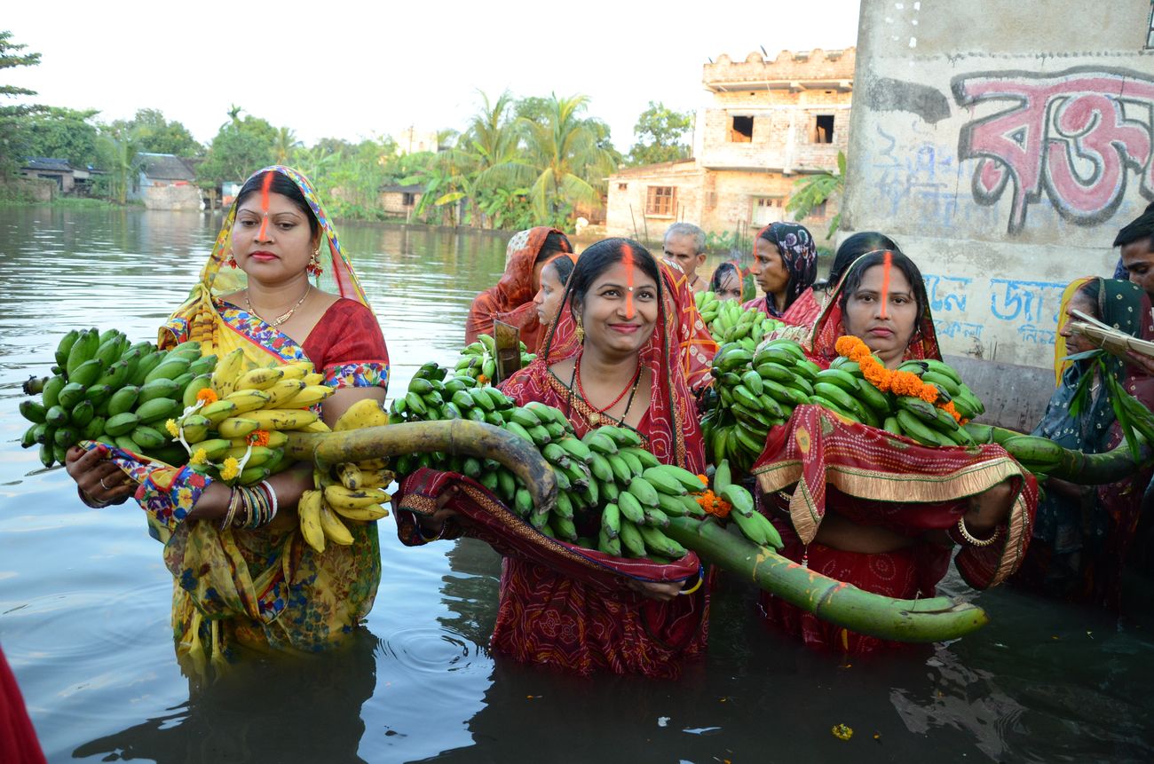 Women standing in the holy river with offerings of bananas and other fruits on the occasion of the ancient Vedic festival of Chhath Puja which is celebrated primarily in Bihar 