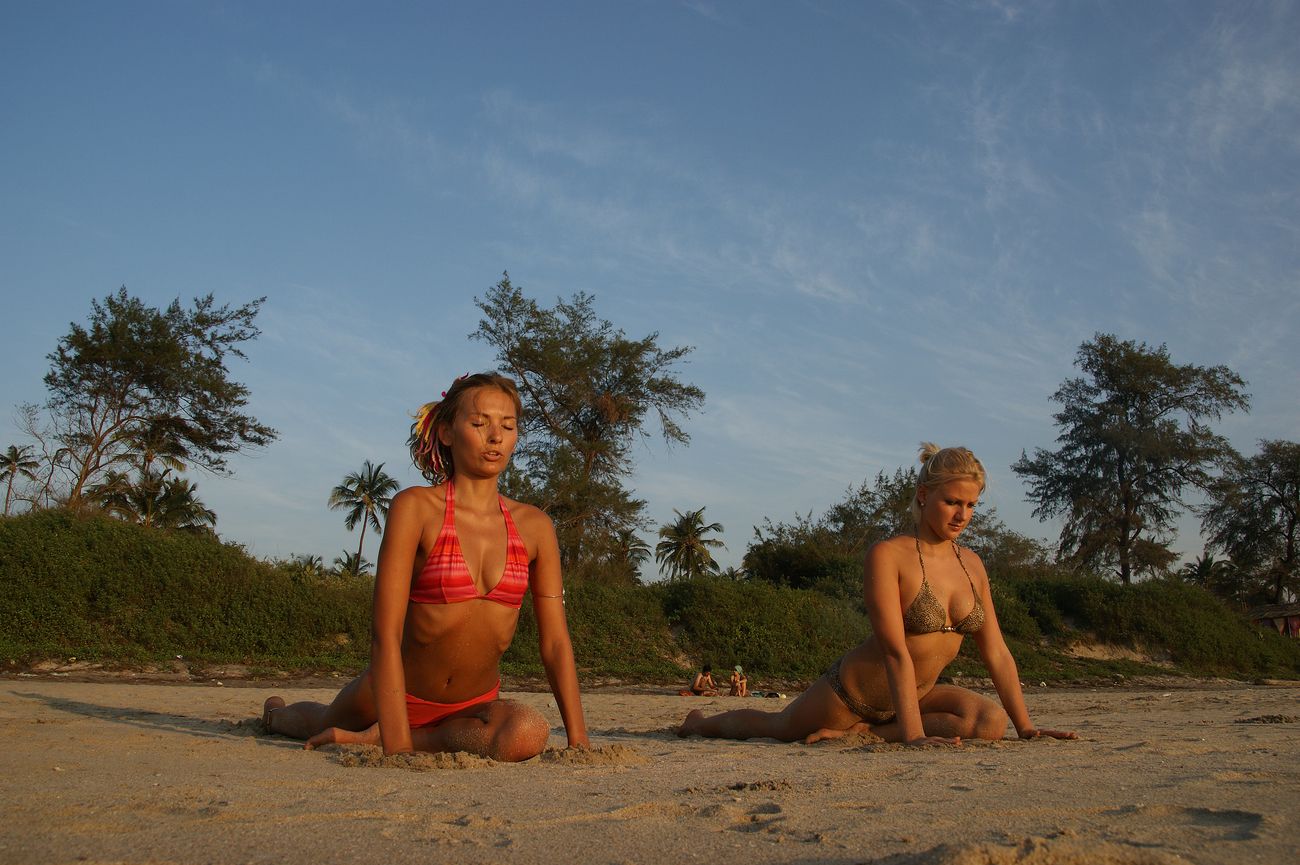 Yoga enthusiasts from outside India visit the Arambol Beach in Goa and practice asanas as the sun sets casting golden light on them