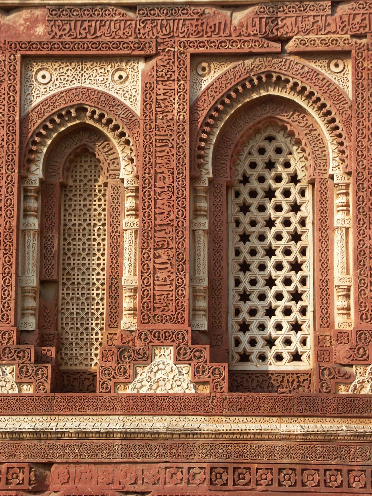intricate carvings on marble and on red sandstone, inscriptions on the wall of a mosque in the qutab minar
