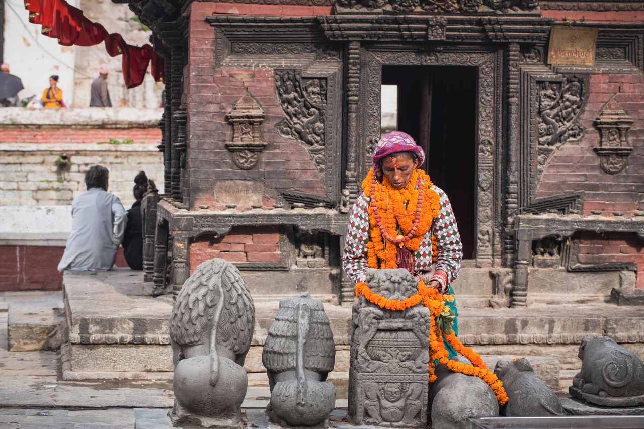 nepali woman hanging flowers and praying pashupatinath kathmandu
