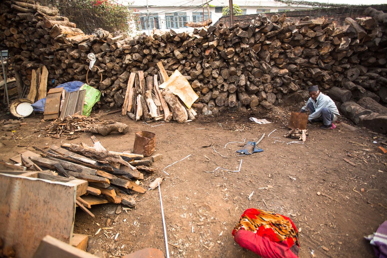 a man sort wood for cremation rites in Bhasmeshvar Ghat